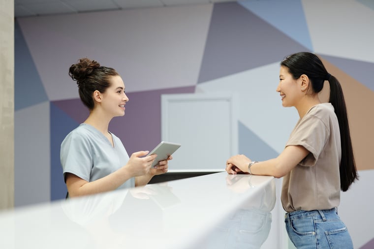 Receptionist with a tablet greeting a patient at the front desk