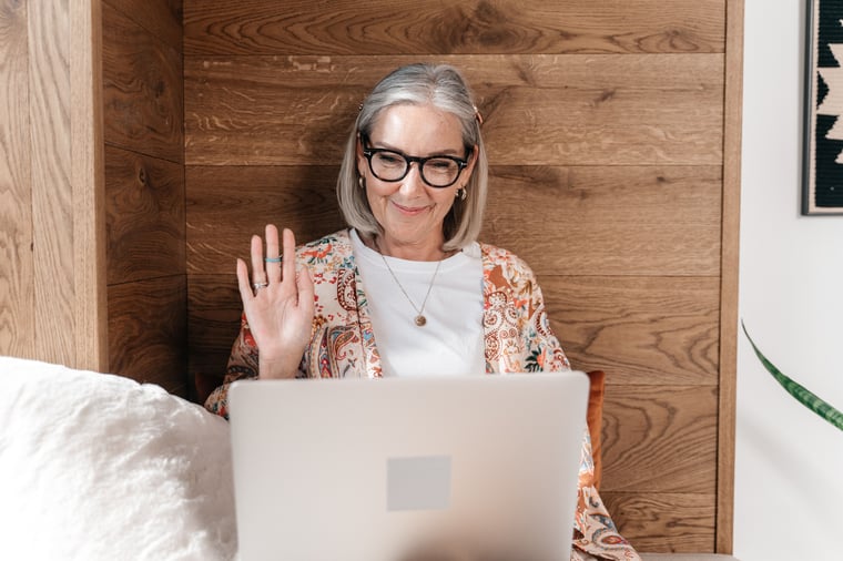 Patient waving hello at the start of a video consult on her laptop