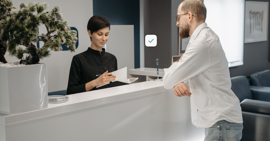 A patient at a reception counter while the receptionist goes through a document with them
